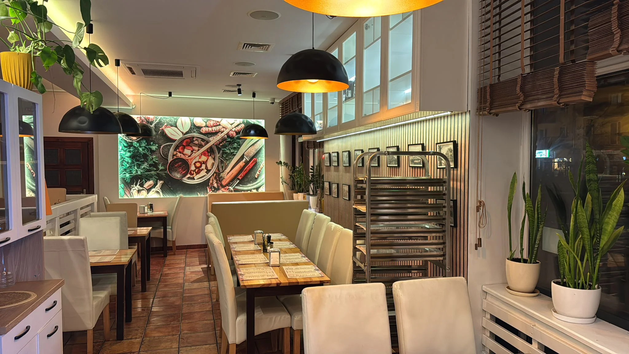 Sala bistro Pobite Gary w Giżycku – stoły i ławy przy ścianie z dekoracją warzywną